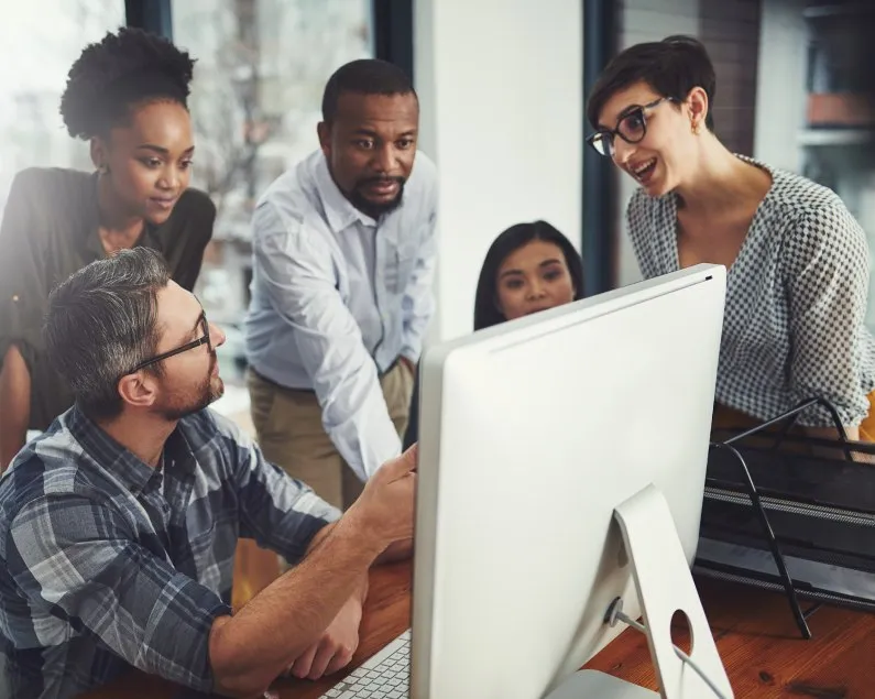 Equipe da SoftConn reunida em frente a um computador